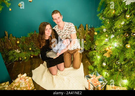 portrait of a young family near the Christmas tree. Happy smiling young family near the Christmas tree. Celebrate New Year. Mom dad and kid at Stock Photo