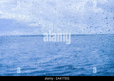Water drops on glass with blue sky in background. Stock Photo