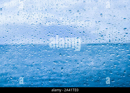 Water drops on glass with blue sky in background. Stock Photo