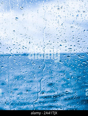 Water drops on glass against blue background Stock Photo