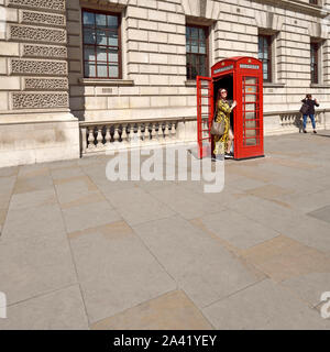 London, England, UK. Japanese woman posing for a photo by a traditional red telephone box Stock Photo