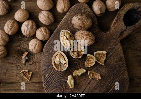 Broken walnut on a rustic wooden board. Flat lay, top view, copy space. Stock Photo