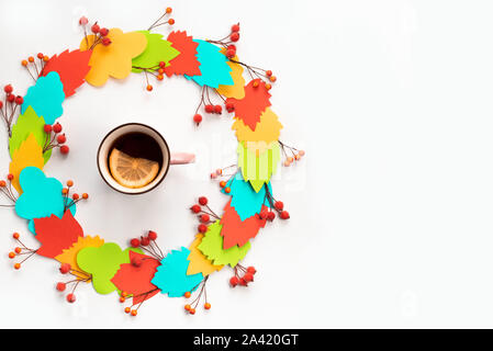 Autumn composition mug with hot tea and lemon. Paper colored leaves branches berries on white background. The concept of autumn. flat lay top view Stock Photo