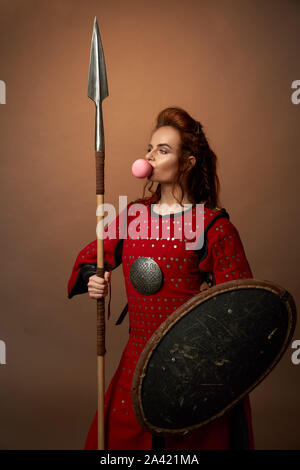 Determined female warrior keeping spear and shield and posing on ...