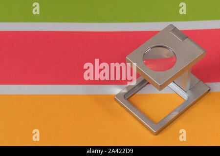 Silver magnifying glass standing on the test print, colored background ...