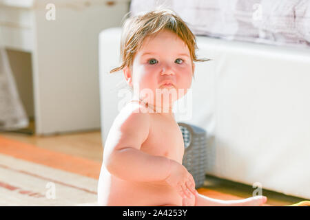child is sitting in the bedroom. Baby boy crawling on bed. Little child playing in white sunny bedroom. Infant kid learning to crawl. Nursery for Stock Photo