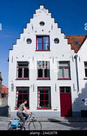 A typical building of Bruges with a stepped gable and a cyclist passing by at speed. Stock Photo