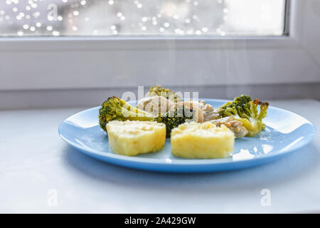 cauliflower with pieces of meat. heart shaped potatoes. on a blue plate. Grilled seafood. Salmon fish steak with greens, broccoli, cauliflower Stock Photo