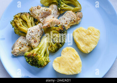 cauliflower with pieces of meat. heart shaped potatoes. on a blue plate. Grilled seafood. Salmon fish steak with greens, broccoli, cauliflower Stock Photo