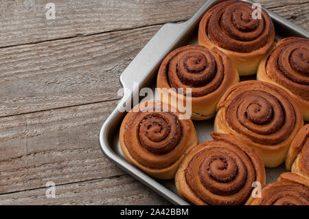 Cinnamon rolls buns on metal baking tray on wooden table Stock Photo