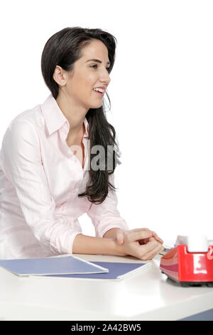 Attractive young woman sat at her desk with documents and telephone Stock Photo