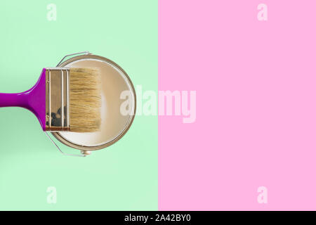 Purple brush with open can of white paint on neo mint and pink background. Trend repairs concept. Stock Photo