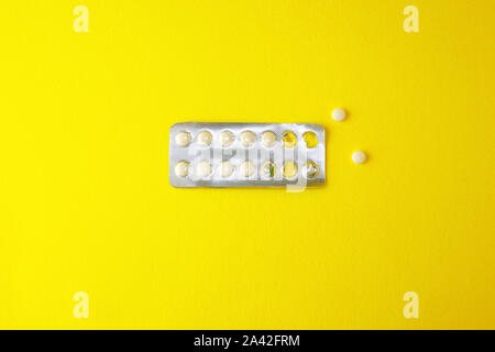 Half-empty blister with white tablets lies on a yellow background. Copy space. Medium plan. Stock Photo