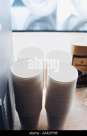 Stacks of white plastic or paper takeaway cups in piles. Stock Photo