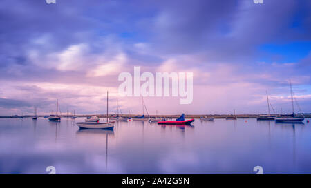 Boats swing on their moorings as the tide comes in on the North Norfolk coast. Stock Photo