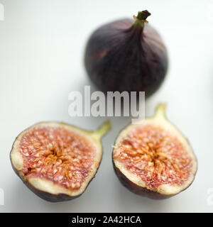 One whole fig and the second cut in half on a white table. Selective focus. Stock Photo