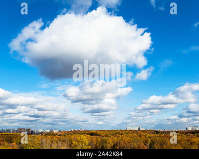chains of cumulus clouds in blue sky over yellow city park on sunny autumn day Stock Photo
