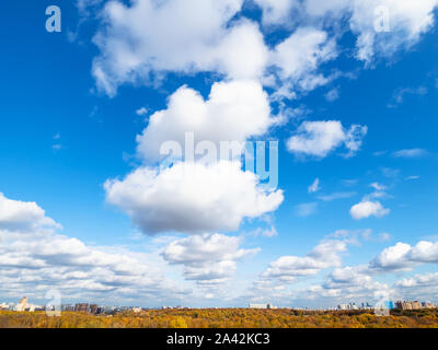 wedge of white cumulus clouds in blue sky over yellow city park on sunny autumn day Stock Photo