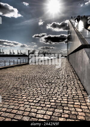 Harbour area in the Hamburg along the river with cranes and buildings in dramatic tone Stock Photo