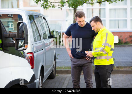 Insurance Agent Examining Car After Accident Claim Being Assessed And Processed By Man On Street Stock Photo