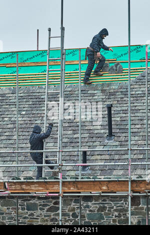 Roof tilers at work on a cloudy, rainy day at Lake Derwentwater, Lake District national park, Cumbria, England. Stock Photo