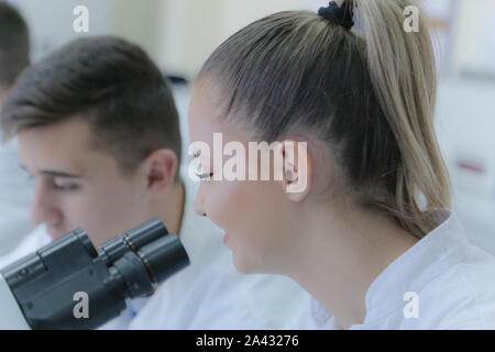 Two young male and female students scientists doing experiments in laboratory. Stock Photo