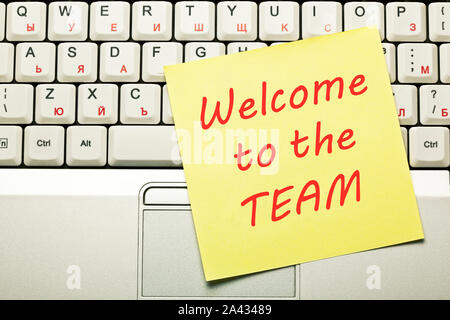 Text Welcome to the Team handwritten on yellow sticky note on laptop keyboard. Stock Photo