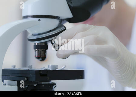 Young male scientist looking through a microscope in a laboratory doing research, microbiological analysis, medicine. Stock Photo