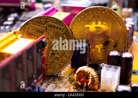 Virtual cryptocurrency money Bitcoin golden coins on a computer printed circuit board PCB. The future of money. Computational equipment. Stock Photo