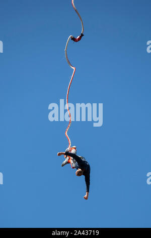 A man jumps with a bungee from a crane top against the blue sky. Unrecognizable person. Stock Photo