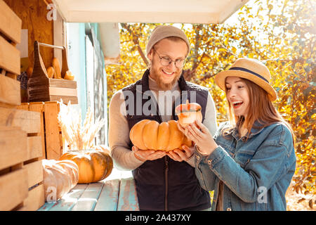 Halloween Preparaton Concept. Young couple decorating house with pumpkins looking at harvest playful Stock Photo