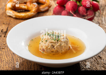 single speckknoedel in soup on wood Stock Photo