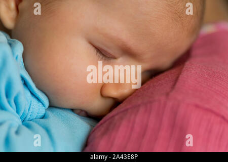 Tender scene: Cute peaceful baby boy sleeping in mother's arms. Stock Photo