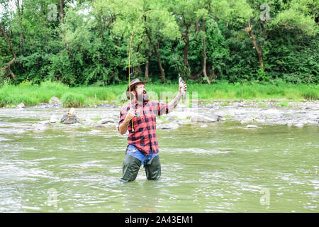 Fishing masculine hobby. Brutal man wear rubber boots stand in river water.  Fisher weekend activity. Fisher with fishing equipment. Fish on hook.  Leisure in wild nature. Fun of fishing is catching Stock Photo - Alamy