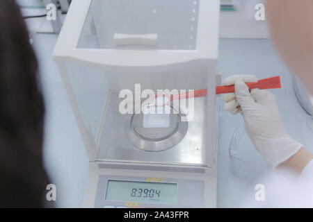 Weighting of ascorbic acid in chemical laboratory.Two multiethnic young female scientists doing experiments in laboratory. Stock Photo