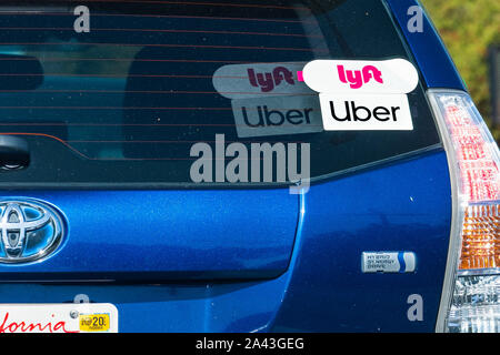 Oct 10, 2019 Mountain View / CA / USA - Lyft and UBER stickers on the rear window of a Toyota Prius Hybrid vehicle offering rides in San Francisco Bay Stock Photo