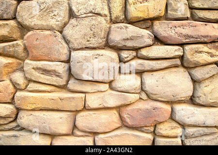 Wall made of light massive natural stones. Beige background for wallpapers. Stock Photo