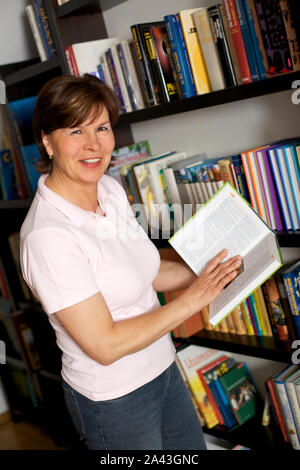 Smiling senior woman carrying books Stock Photo