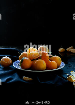 Fresh spanish mandarin oranges fruit with leaves on rustic table, dark and moody style Stock Photo