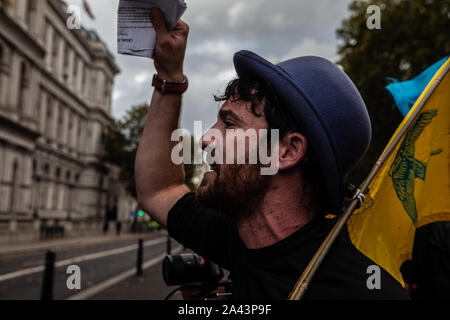 London, UK. 8th Oct, 2019. A protester shouts slogans during the demonstration.Thousands of protesters take to the streets in London calling on the UK government to tackle climate change in what they are calling ''˜Rebellion Week'. Causing mass disruption in central London by blocking roads and disturbing the usual workings of government. Boris Johnson, the British Prime Minister, responded to the protest with anger and frustration. At an event in London on Monday, Mr. Johnson referred to the demonstrators as ''˜crusties' and suggesting that they 'stop blocking the traffic Stock Photo