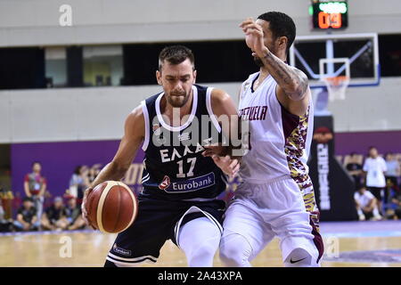 A basketball player of Greece, left, keeps the ball while defended by a member of Venezuela, right, during 2019 Suzhou International Basketball Challe Stock Photo