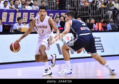 A basketball player of Venezuela, left, keeps the ball while defended by a member of Greece, right, during 2019 Suzhou International Basketball Challe Stock Photo