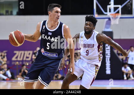 A basketball player of Greece, left, keeps the ball while defended by a member of Venezuela, right, during 2019 Suzhou International Basketball Challe Stock Photo