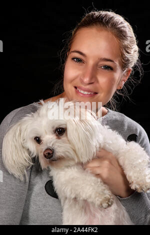 Woman with her best friend, her dog, posing for a portrait on black background. Stock Photo