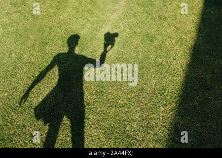 The shadow of the photographer with camera on the lawn at mid summer sunny day Stock Photo