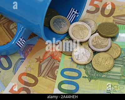 euro coins fall out of greek cup on euro banknotes background. finance concept Stock Photo