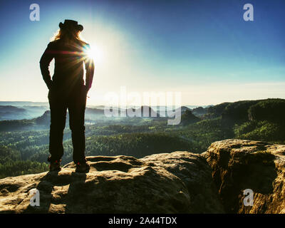 Successful woman hiker cheking the altitude on the top of sandstone sharp cliff edge. Stock Photo