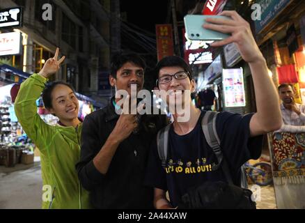 Kathmandu, Nepal. 7th Oct, 2019. Amit Baniya (C) poses for a photo with Chinese tourists in Kathmandu, Nepal, Oct. 7, 2019. Anyone hearing Amit Baniya's Mandarin would think the 23-year-old young man is Chinese. He knows almost all the buzzwords on the Chinese social media and is also an expert in using trending words and phrases to attract TikTok fans. TO GO WITH:Feature: Nepali TikTok celebrity invites all Chinese to visit his country Credit: Liu Tian/Xinhua/Alamy Live News Stock Photo