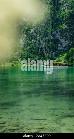 A tourist boat is cruising over the colorful Koenigssee lake (Königssee) in Bavaria, Germany Stock Photo