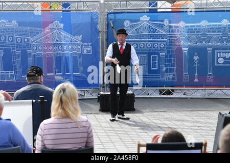 2019. Edinburgh Festival. Street Performer on Princess Street does his knife juggling act to his audience. Stock Photo